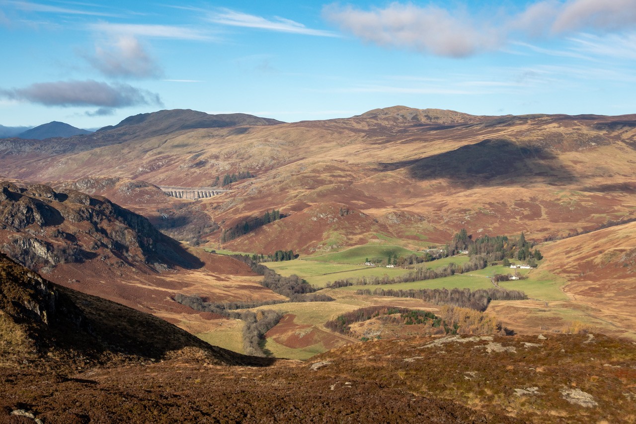 A view over the Invergeldie Estate - heather covered mountains under a blue sky