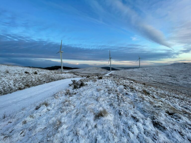 White wind turbines on snow covered ground under blue sky during daytime