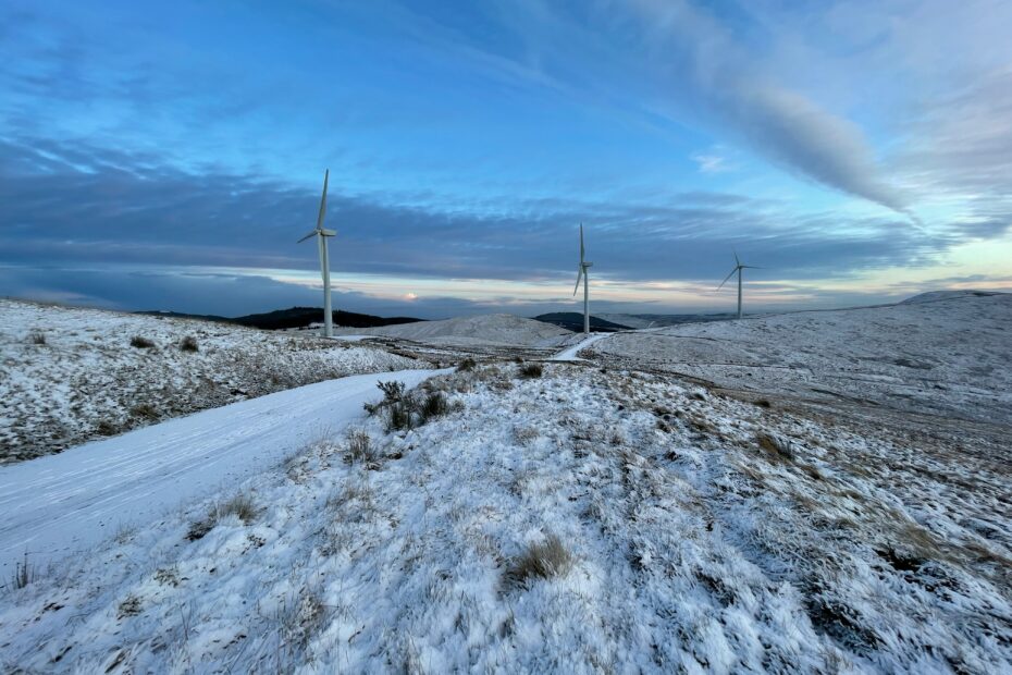 White wind turbines on snow covered ground under blue sky during daytime