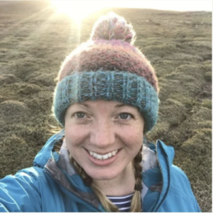 A woman wearing a knit cap smiles into the camera